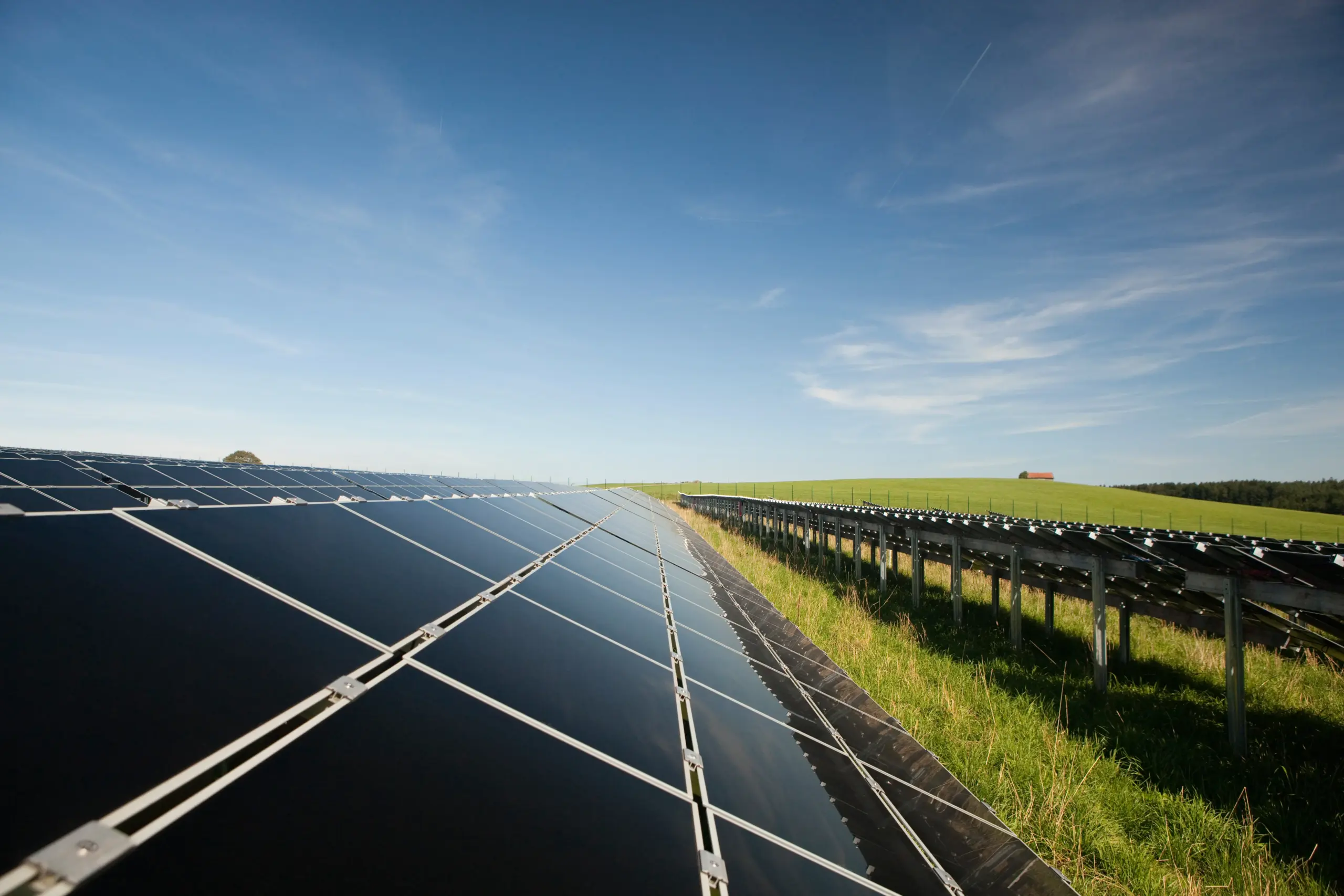 Großflächige Photovoltaikanlage auf freiem Feld mit Reihen aus Solarmodulen unter blauem Himmel. - Deutsch Marketing